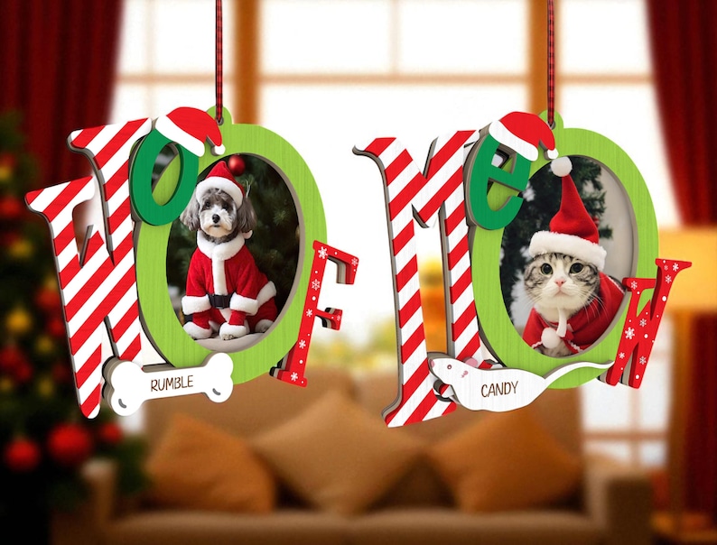 May include: Two Christmas ornaments with the word "NOEL" in red and white striped letters. One features a dog in a Santa suit, the other a cat in a Santa suit. The dog ornament has the name "RUMBLE" and the cat ornament has the name "CANDY".