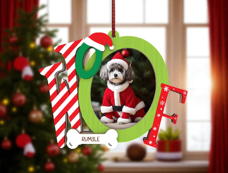 May include: A Christmas ornament with the word "HOPE" in red and white striped letters and green letters. The "O" frames a photo of a dog in a Santa suit. A bone-shaped tag reads "RUMBLE".