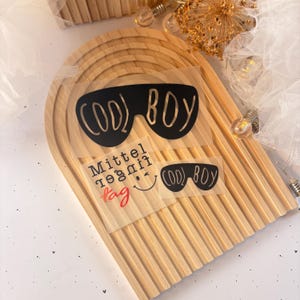 Könnte beinhalten: Zwei transparente Aufkleber mit schwarzem Text und Sonnenbrillen-Grafiken. Der obere Aufkleber sagt "COOL BOY" und der untere Aufkleber sagt "Mittel regnif tag" mit einem Smiley und "COOL BOY" mit Sonnenbrille.