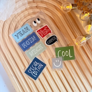 Könnte beinhalten: Ein Set bunter Sticker mit verschiedenen Sprüchen und Designs, darunter "Yeah", "Moin", "Nice", "Yes", "Super", "Cool", "Special Edition" sowie ein Augenpaar und ein Smiley.