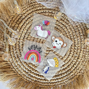 Könnte beinhalten: Vier bunte Bügelbilder mit einem Einhorn mit Ballons, einem Regenbogen mit einem Herzen, einem Affen mit herausgestreckter Zunge und einem Fuchs mit einer Krone.