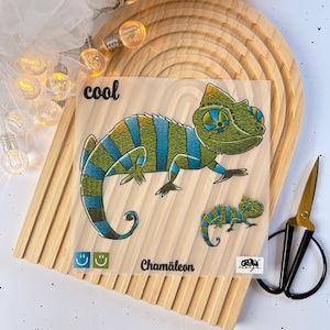 Könnte beinhalten: Ein transparentes Blatt mit einer Illustration eines grünen und blauen Chamäleons. Das Chamäleon ist gestreift und hat ein großes, rundes Auge. Der Text "cool" und "Chameleon" ist auf dem Blatt gedruckt.