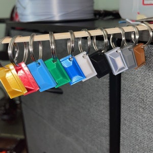 May include: A set of ten keychains with different colored plastic charms. The charms are rectangular and have a smooth, glossy finish. The keychains are attached to silver key rings.