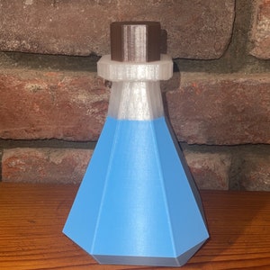 Puede incluir: Una botella de vidrio azul con un tapón de corcho marrón. La botella está sobre una superficie de madera.