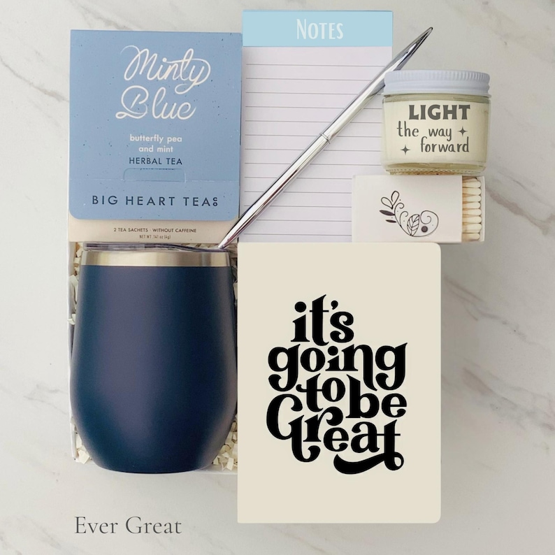 Pode incluir: Um conjunto de presentes com um copo t&eacute;rmico azul marinho, um bloco de notas, uma caneta, uma vela, f&oacute;sforos, uma caixa de ch&aacute; de ervas e um caderno com o texto "it's going to be great". A caixa de ch&aacute; diz "Minty Blue".