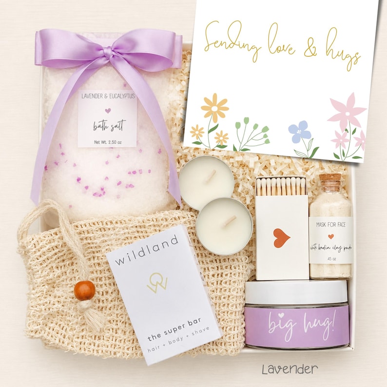Puede incluir: Una caja de regalo que contiene una bolsa de sales de ba&ntilde;o de lavanda y eucalipto con un lazo morado, dos velas de t&eacute;, una caja de cerillas, una mascarilla facial de arcilla blanca, una pastilla de jab&oacute;n y una tarjeta que dice Sending love & hugs.