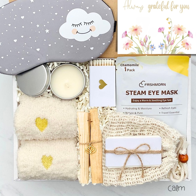 May include: A gift box with a gray sleep mask, a candle, a box of matches, two small towels with gold heart embroidery, and a steam eye mask. The box also contains a card with floral illustrations and the text "Always grateful for you."
