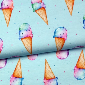 Könnte beinhalten: Hellblauer Stoff mit einem sich wiederholenden Muster aus Aquarell-Eistüten. Jeder Kegel hat ein lächelndes Gesicht und ist mit Kugeln aus blauem, rosa und grünem Eis bedeckt. Kleine bunte Punkte sind über den Hintergrund verstreut.