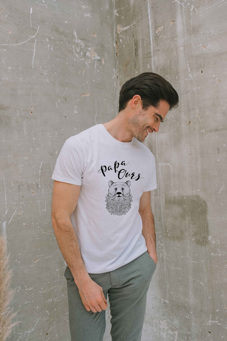 May include: White t-shirt with a black and white illustration of a bear with a beard and the text "Papa Ours" on the front.