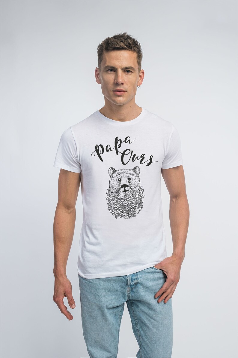 May include: White t-shirt featuring a black and white illustration of a bear with a moustache and beard. The text "Papa Ours" is written in black cursive above the bear.