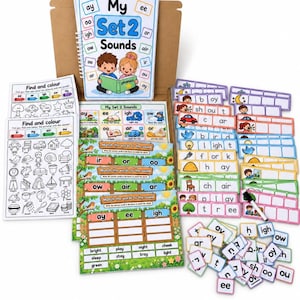 May include: A phonics learning kit featuring a spiral-bound book titled My Set 2 Sounds, multiple activity sheets with Find and Colour text, matching worksheets, colorful word tiles, and a dry-erase marker, all organized in a cardboard box.