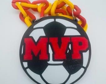May include: A red, white, and black soccer ball keychain with the word "MVP" in red letters. The keychain is attached to a chain of red and yellow plastic links.