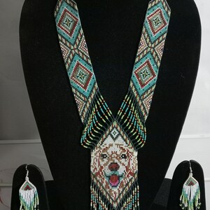 May include: A beaded necklace and earrings set with a dog's face in the center of the necklace. The necklace is made of black, white, green, red, and blue beads. The earrings are made of white, green, and blue beads.