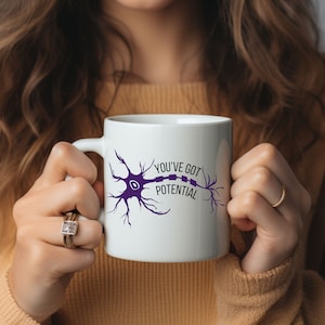May include: White ceramic mug featuring a purple neuron graphic and the text "You've got potential".