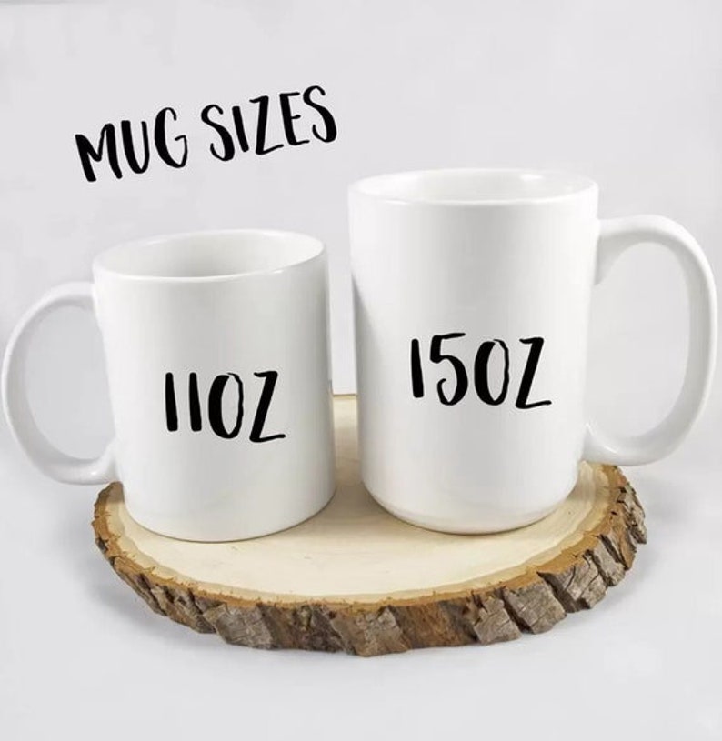 Peut inclure: Deux mugs en c&eacute;ramique blanche, l'un &eacute;tiquet&eacute; "11oz" et l'autre "15oz", sont pos&eacute;s sur une tranche de bois. Le texte "MUG SIZES" est au-dessus des mugs. Les mugs ont un design classique et simple avec une anse incurv&eacute;e.