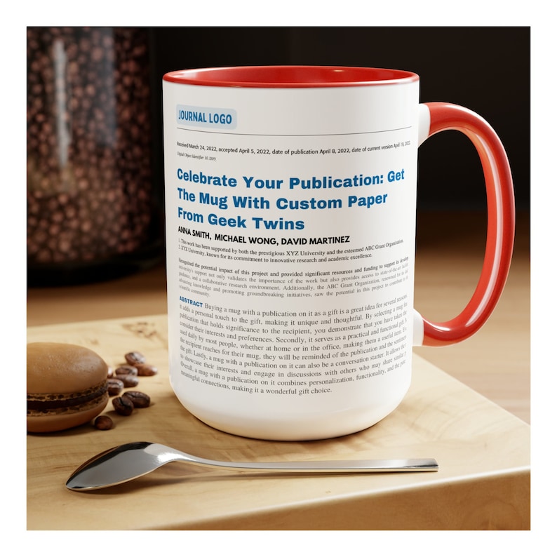 Op de afbeelding: Een witte keramische mok met een rode rand en handvat. De mok heeft een tekstontwerp met de tekst "Celebrate Your Publication: Get The Mug With Custom Paper From Geek Twins".
