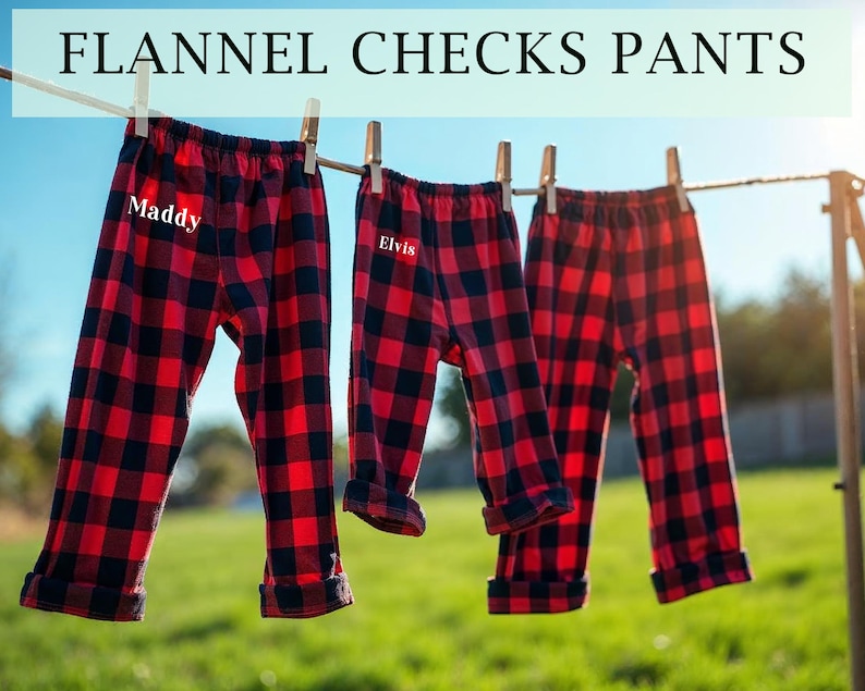 May include: Two pairs of red and black plaid flannel pajama pants hanging on a clothesline. One pair has the name "Maddy" embroidered on the front and the other pair has the name "Elvis" embroidered on the front.