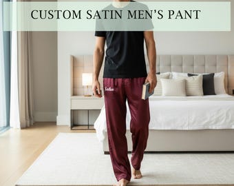 May include: A pair of maroon satin lounge pants featuring the name John embroidered in white script on the upper thigh. The pants are paired with a plain black short-sleeved t-shirt. The text CUSTOM SATIN MEN'S PANT appears at the top.