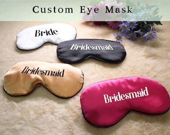 Op de afbeelding: Vier satijnen oogmaskers in verschillende kleuren en met tekst. De maskers zijn wit, zwart, goud en roze. De tekst op de maskers luidt "Bride", "Bridesmaid", "Bridesmaid" en "Bridesmaid".
