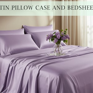 May include: A bed dressed with lavender satin pillowcases and bedsheets. The sheets are neatly arranged, with the pillowcases in place. A vase of purple flowers sits on the bed, adding a touch of colour to the scene.