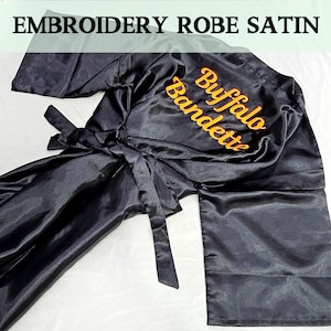 May include: Black satin robe with a gold embroidered inscription that reads "Buffalo Bridette".