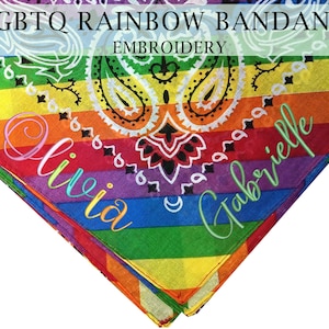 Könnte beinhalten: Regenbogenfarbenes Bandana mit dem Text "LGBTQ Rainbow Bandana Embroidery". Mit Paisley-Muster und den Namen "Olivia" und "Gabrielle" in Schreibschrift. Das Bandana ist dreieckig gefaltet.