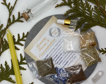 May include: An assortment of items for memory and focus, including a small glass bottle, a dropper bottle, a yellow candle, and small bags of herbs and crystals. The items are arranged on a gray circular surface with text that reads "Memory, Focus, & Concentration."