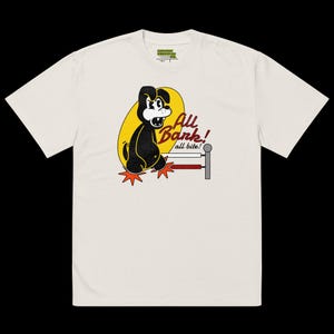 Può includere: T-shirt color crema con un cane dei cartoni animati e la scritta "All Bark! all bite!" in un ovale giallo. Il cane è nero con dettagli bianchi e piedi a forma di stella rossi. La maglietta ha maniche corte.