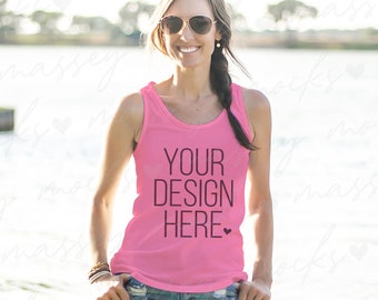 May include: A pink tank top with the text "YOUR DESIGN HERE" in black. The model is wearing the tank top with denim shorts and sunglasses.
