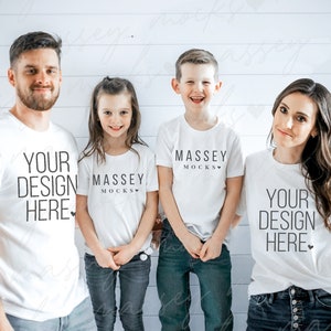 May include: Four people wearing white t-shirts and jeans pose for a photo. The shirts feature the text "YOUR DESIGN HERE" and "MASSEY MOCKS" in black. The background is a white wooden wall.