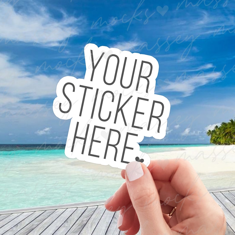 May include: White sticker with black text that says "YOUR STICKER HERE" with a small heart symbol. The sticker is being held by a hand against a background of a tropical beach scene.