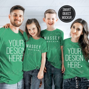 Pode incluir: Uma família de quatro pessoas vestindo camisetas verdes com o texto "Your Design Here" e "Massey Mocks" impresso nelas. As camisetas são de um verde brilhante e o texto é branco. A família está em pé em frente a um fundo de painel de madeira branco.