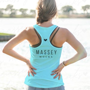 Puede incluir: Un top de tirantes azul claro con un corazón negro y el texto "MASSEY MOCKS" en la espalda.