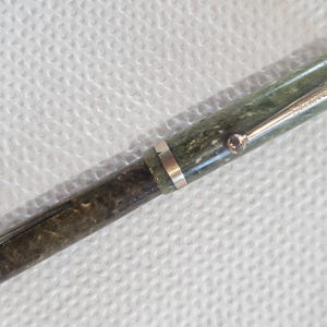May include: A vintage fountain pen with a marbled green and brown body and silver-colored accents. The pen has a clip and a band near the center. The pen's cap has the word "Waterman's" engraved on it.