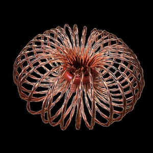 May include: A kinetic sculpture composed of numerous interconnected copper-colored wire loops forming a spherical, cage-like structure. The wires radiate from a central red ring, creating a flexible, expandable, and collapsible geometric pattern.