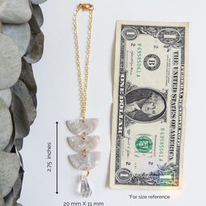 May include: A gold-tone chain ornament featuring three stacked semi-circular white marbled acrylic pieces and a clear teardrop crystal. The total length is 7 inches, the acrylic section is 2.75 inches, and the crystal measures 20 mm by 11 mm.