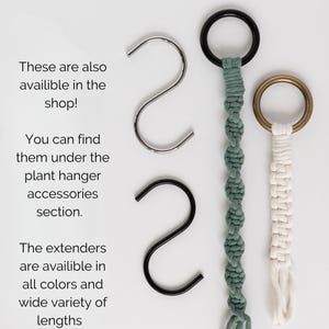Op de afbeelding: Twee metalen S-haken in zilver en zwart, naast twee macram&eacute; plantenhangerverlengstukken. E&eacute;n verlengstuk is saliegroen met een zwarte ring, de andere is gebroken wit met een bronzen ring. Tekst: Need an S-hook or extender to go with your plant hanger? These are also availible in the shop! You can find them under the plant hanger accessories section. The extenders are availible in all colors and wide variety of lengths.