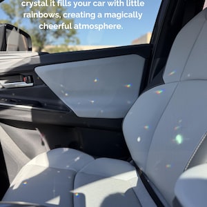 May include: The interior of a car with light gray seats and door panels featuring small, colorful light refractions from a crystal. The text reads: When direct sunlight hits the crystal it fills your car with little rainbows, creating a magically cheerful atmosphere.