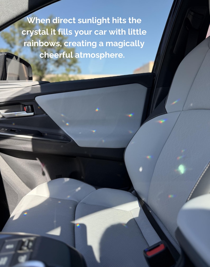 May include: The interior of a car with light gray seats and door panels featuring small, colorful light refractions from a crystal. The text reads: When direct sunlight hits the crystal it fills your car with little rainbows, creating a magically cheerful atmosphere.