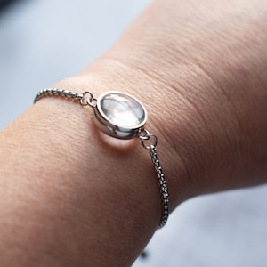 May include: A silver chain bracelet with a clear glass circle pendant.