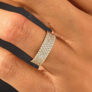 May include: A gold band ring with a row of small diamonds set in a pave setting.