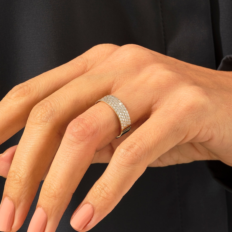 May include: A gold band ring with a row of small diamonds set in a pave setting.