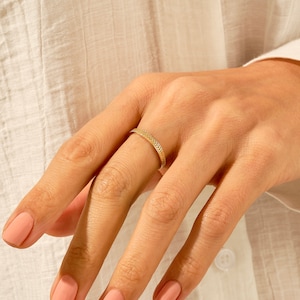 Könnte beinhalten: Ein goldener Ring mit geflochtenem Design.