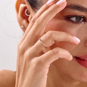 Puede incluir: Un delicado anillo de oro con una fila de peque&ntilde;as y vibrantes piedras preciosas rosas. El anillo tiene un dise&ntilde;o minimalista, con las piedras preciosas muy juntas. Esta elegante joya a&ntilde;ade un sutil toque de color y brillo.