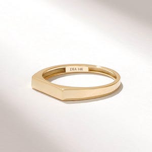 May include: A polished 14K yellow gold ring featuring a flat, rectangular top surface. The interior of the band is clearly engraved with the text DIA 14K, indicating the metal purity. The ring has a smooth, reflective finish and a simple band.