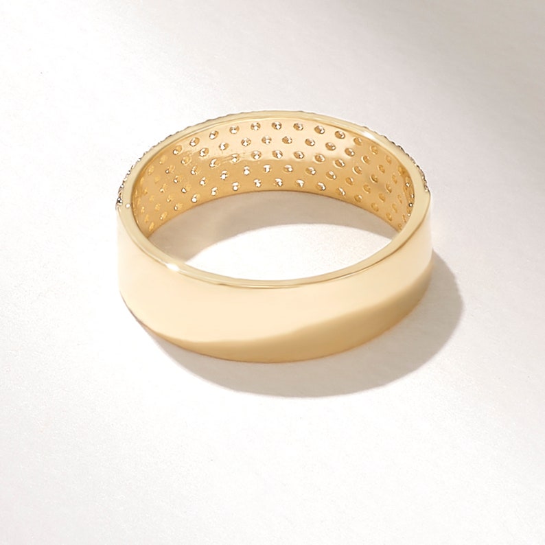 May include: A gold band ring with a row of small clear stones around the top edge.