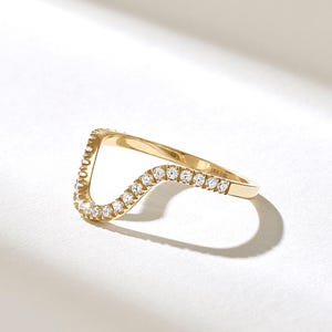 May include: A 14K gold chevron-shaped ring featuring a row of small, round, clear pavé-set diamonds along the top edge. The interior of the band is clearly stamped with the text DIA 14K, indicating the metal purity and diamond content.