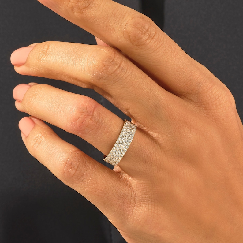 May include: A gold band ring with a row of small diamonds set in a pave setting.