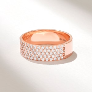 May include: A rose gold band ring with a row of pave set diamonds. The ring is marked "DIA 14K" on the inside.