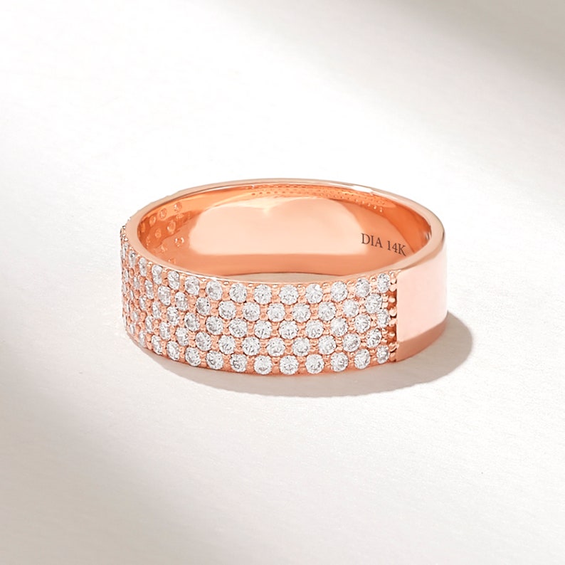 May include: A rose gold band ring with a row of pave set diamonds. The ring is marked "DIA 14K" on the inside.